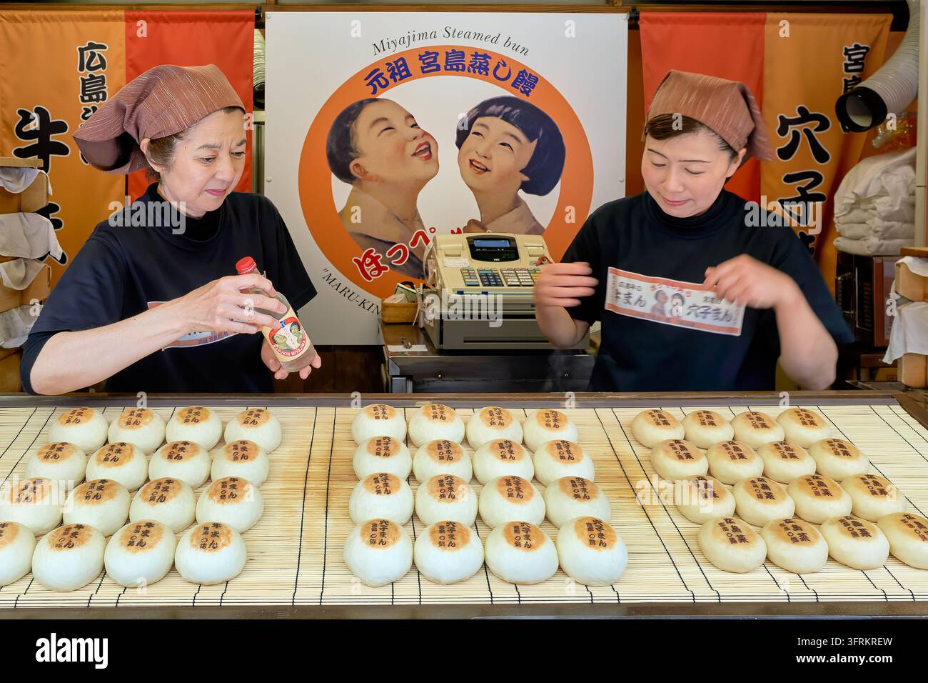 Due donne con foulard sistemano carne di manzo, anguille e verdure di Hiroshima su stuoie di bambù in uno snack shop sull'isola di Itsukushima, Hiroshima Foto Stock