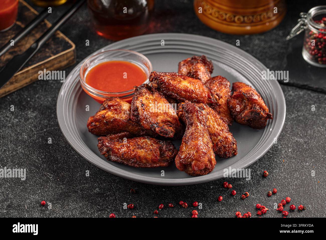 Alette di pollo piccanti con salsa su piatto grigio Foto Stock