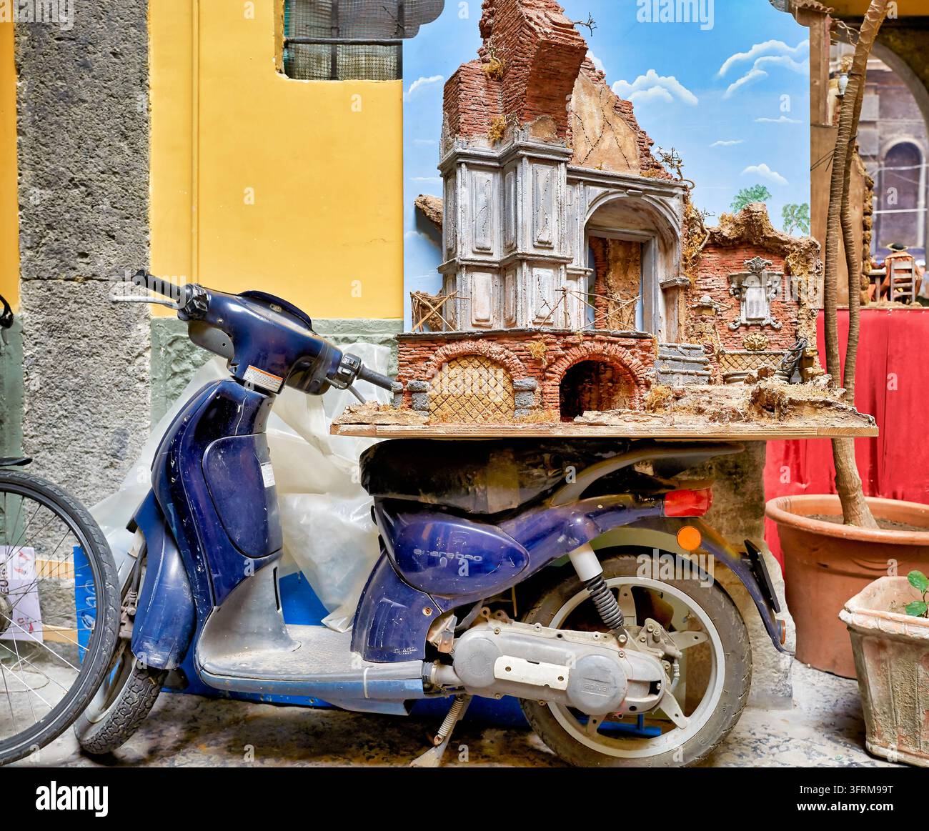 Rovina di presepe napoletano con archi in mattoni e facciata classica posizionata sul sedile di uno scooter blu, stagione natalizia, Campania, Italia Foto Stock