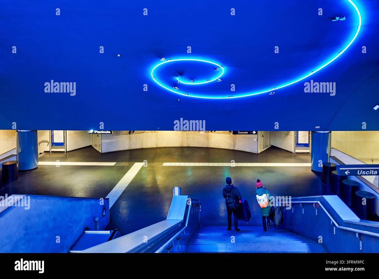 Due viaggiatori con bagagli scendono le scale sotto un'opera d'arte luminosa basata sulla sequenza di Fibonacci, Metropolitana di Napoli, Campania, Italia Foto Stock