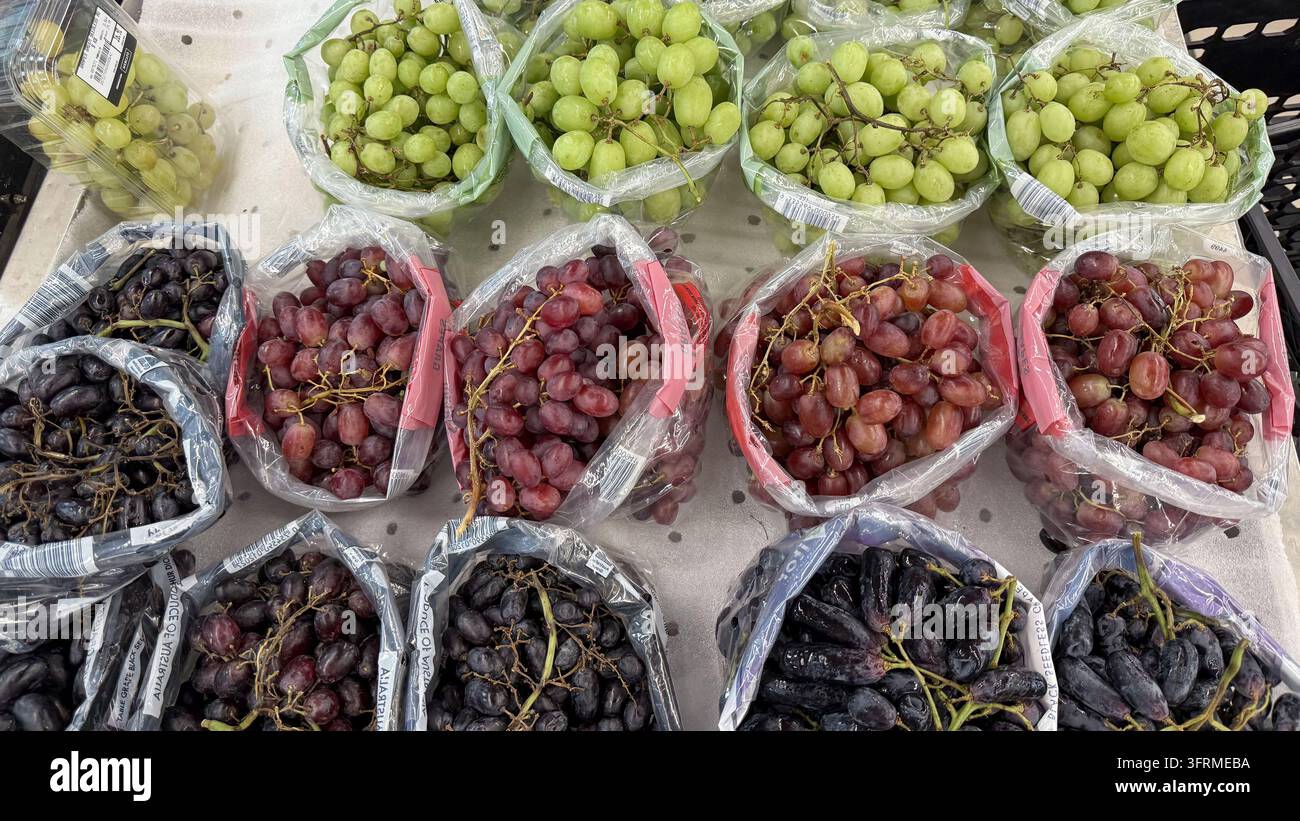 Uva verde, rossa e nera assortita esposta in contenitori in un mercato di prodotti. Sfondo alimentare con spazio per la pubblicità di generi alimentari, alimentazione sana Foto Stock