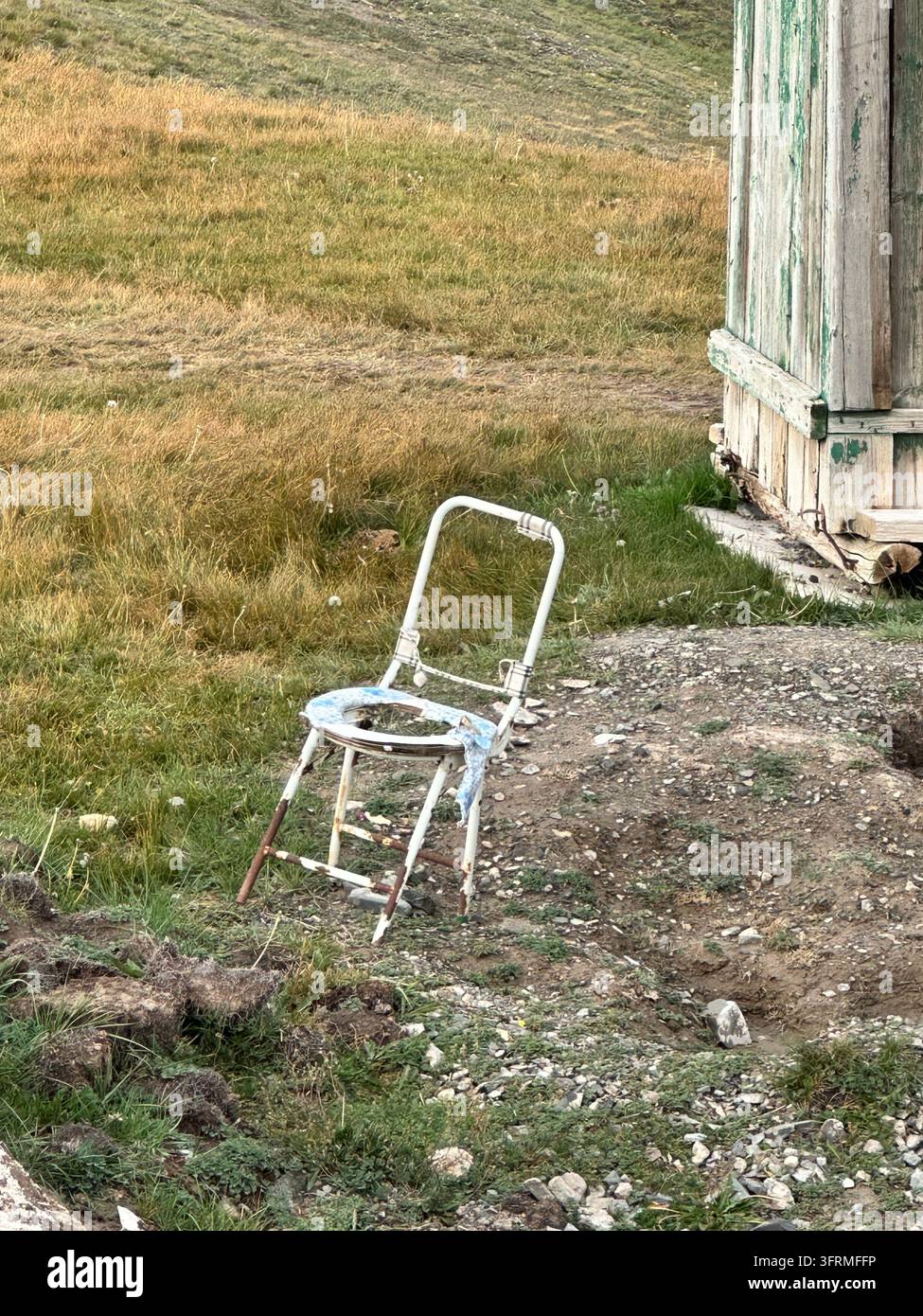 Trono con vista: una sedia rotta con un buco funge da toilette all'aperto di un accampamento remoto vicino al lago Kel-Suu, in Kirghizistan Foto Stock