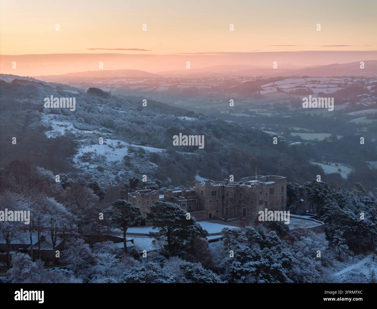 Alba su Castle Drogo coperto di neve in una fredda mattina d'inverno, Dartmoor National Park, Devon, Inghilterra. Inverno (dicembre) 2023. Foto Stock
