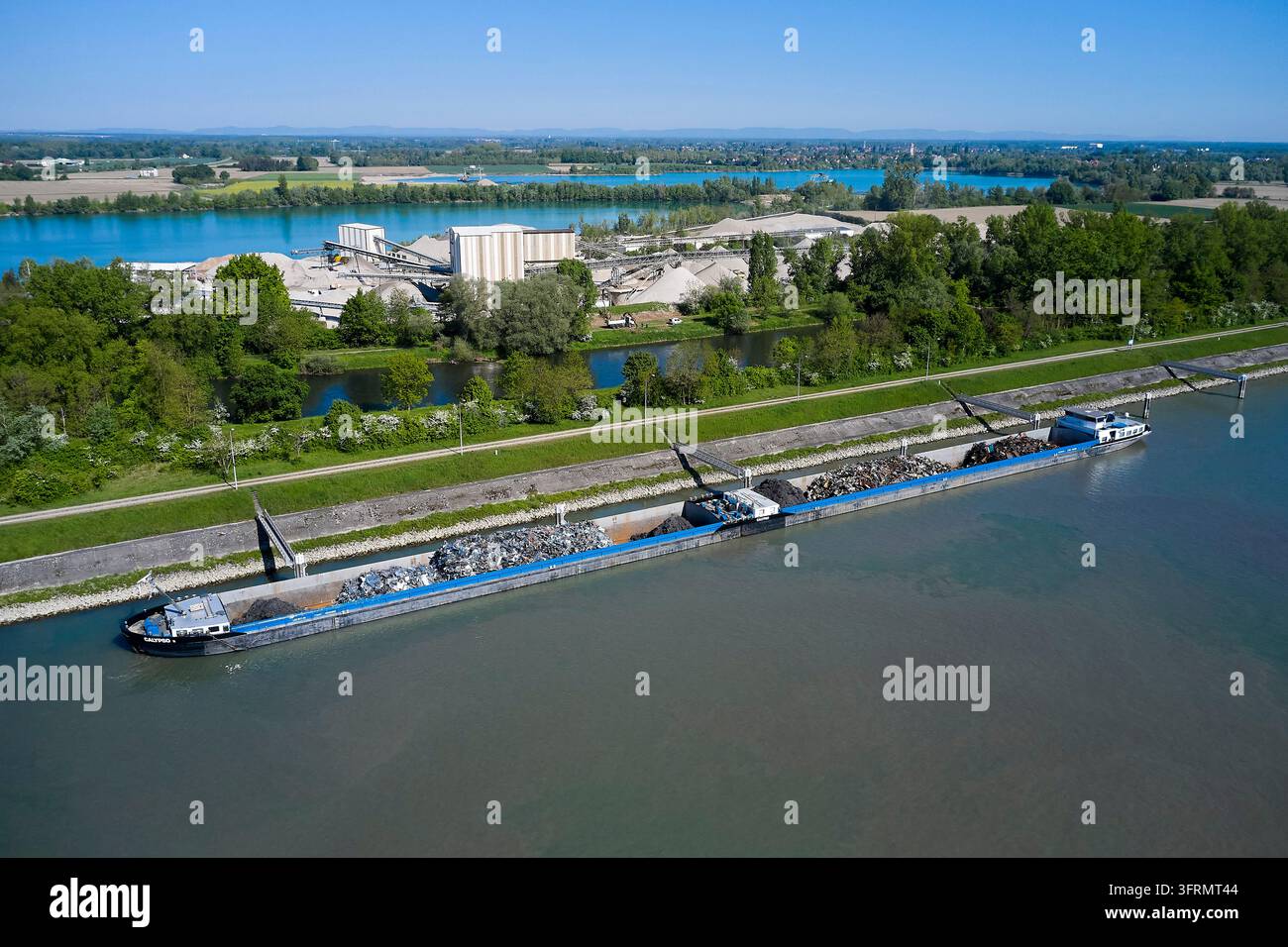 Navigazione sulle vie d'acqua interne vicino alla chiuse di Gambsheim sul Reno e alla cava di sabbia e ghiaia Veltz-Vix. Chiatte per il trasporto di metalli e ferri vecchi Foto Stock