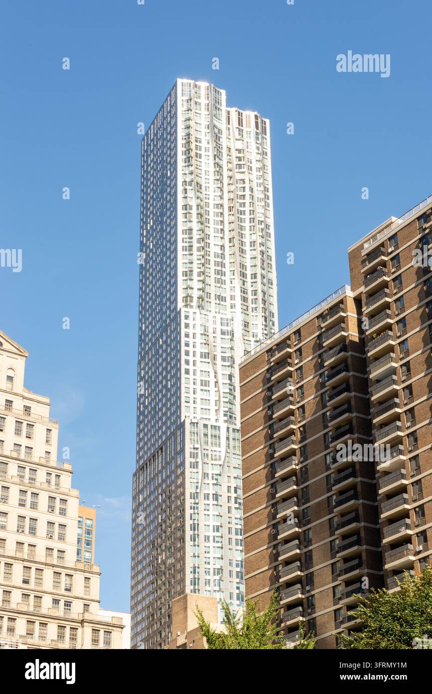 Vista ad angolo basso di stili architettonici contrastanti a Manhattan, New York City, con grattacieli moderni in vetro che circondano un edificio tradizionale in pietra Foto Stock