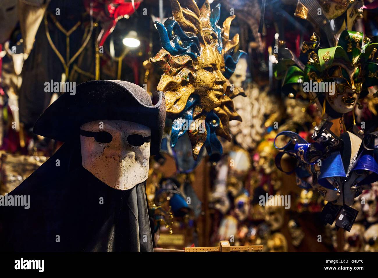Maschere tradizionali del Carnevale di Venezia esposte in un negozio a Venezia, Italia, con una misteriosa maschera Bauta e un ornato volto solare dorato. Foto Stock