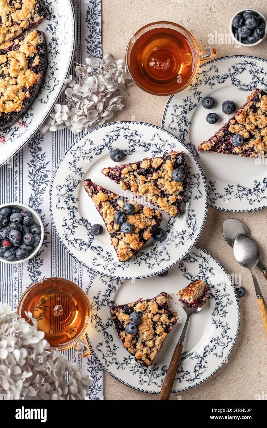 Torta o crostata al crumble di farina d’avena cotta al forno con mirtilli freschi su piatti di ceramica serviti per il tè, vista dall’alto. Menu, ricetta Foto Stock