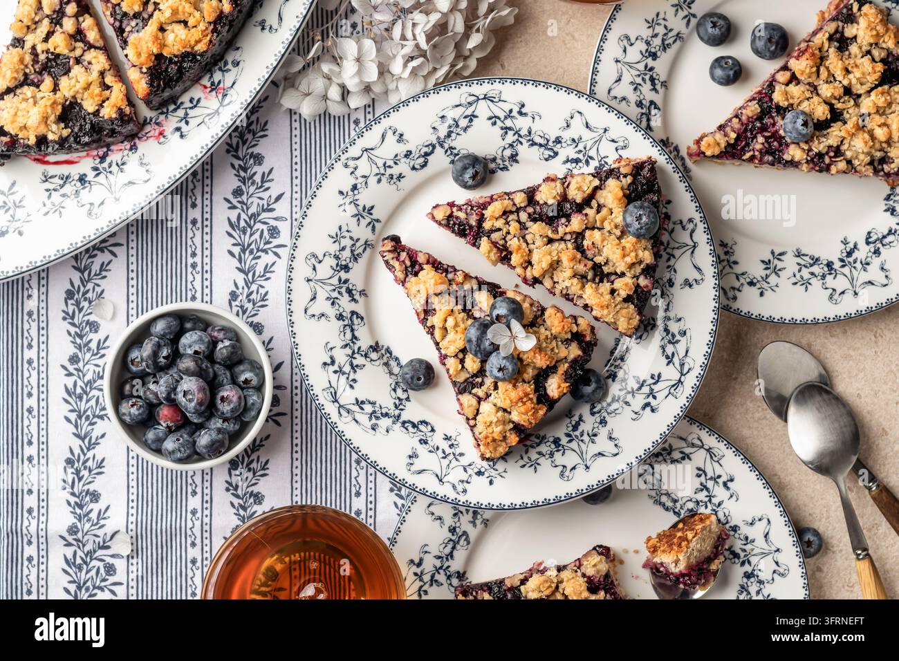 Torta o crostata al crumble di farina d’avena cotta al forno con mirtilli freschi su piatti di ceramica serviti per il tè, vista dall’alto. Menu, ricetta Foto Stock