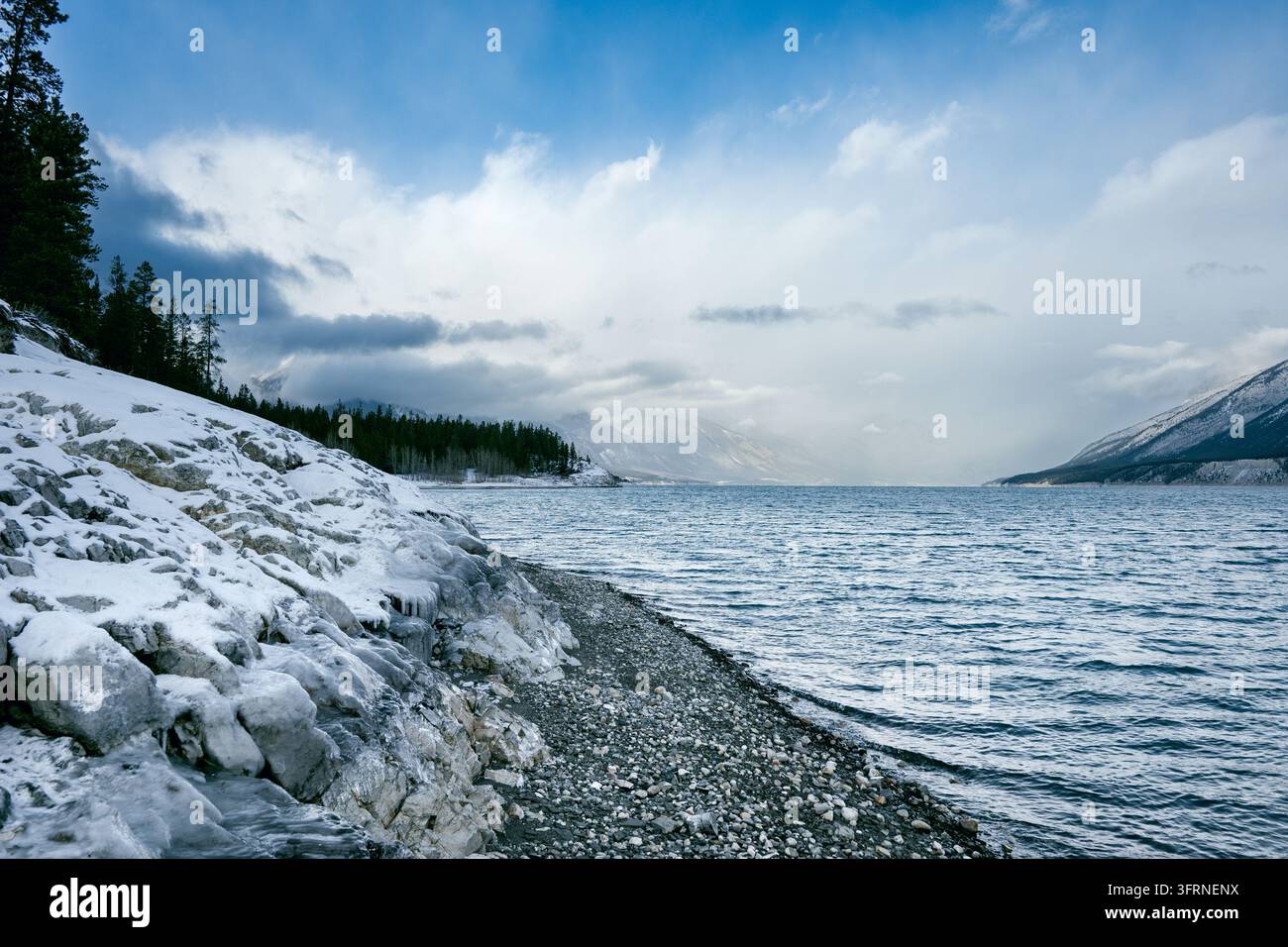 Vista grandangolare a livello degli occhi di una riva rocciosa ghiacciata all'Abraham Lake, Alberta, Canada, con rocce coperte di ghiaccio, brina, ghiaccioli, spiaggia di ciottoli, profonda Foto Stock