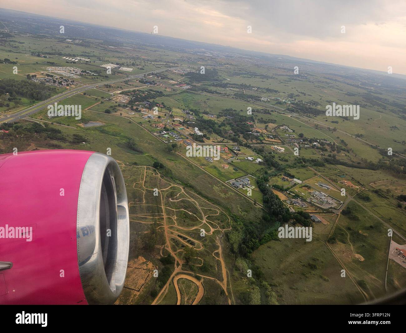 Un'ala di aereo rosa è visibile in volo. L'ala è sul lato sinistro dell'immagine a Johannesburg in Sudafrica Foto Stock