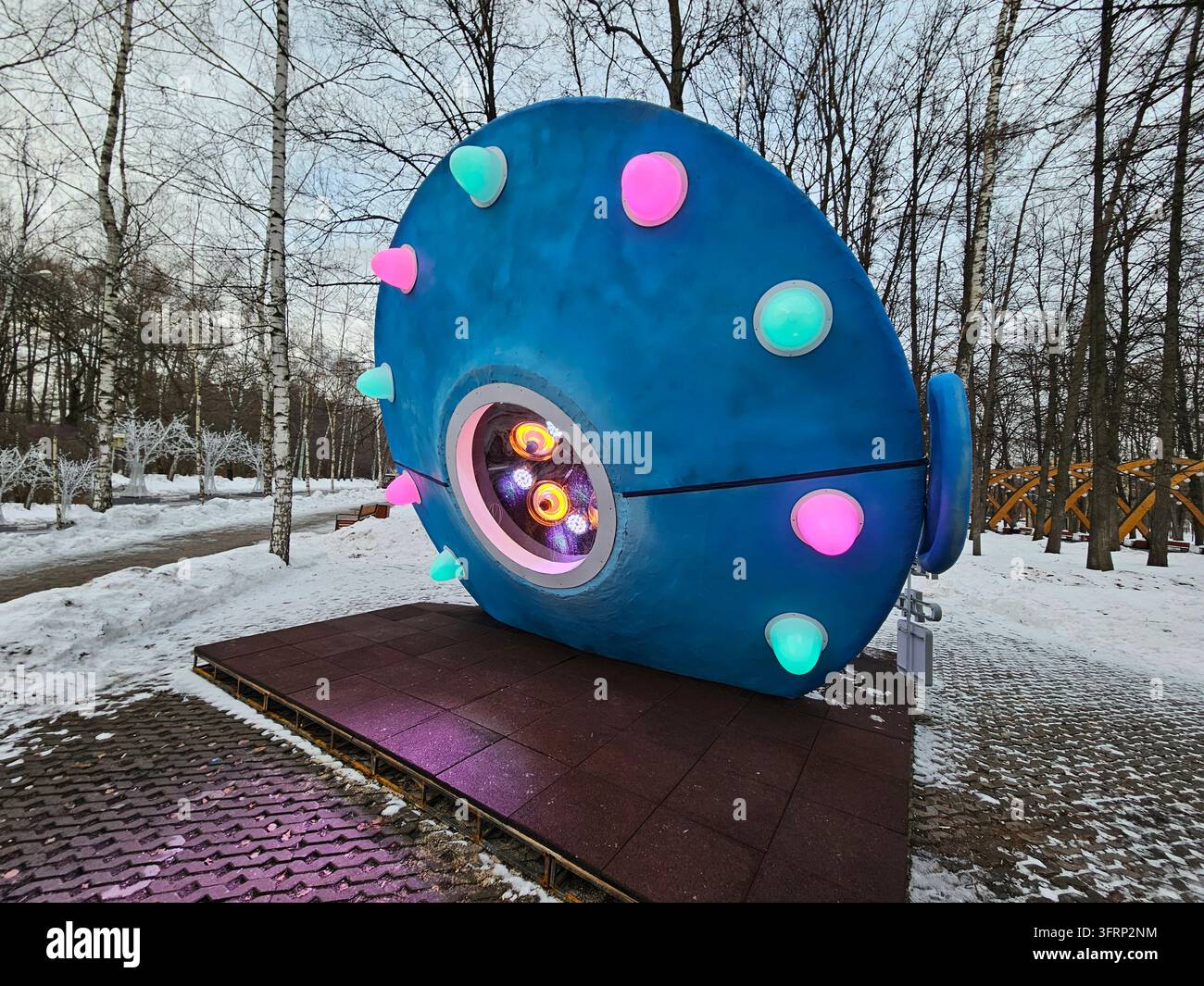 Mosca - 22 dic. 2023: Oggetto pubblicitario a forma di piatto volante UFO blu con una grande finestra e riscaldatore luminoso su di esso. La struttura ai colori diversi si trova in una zona innevata a Sokolniki Foto Stock