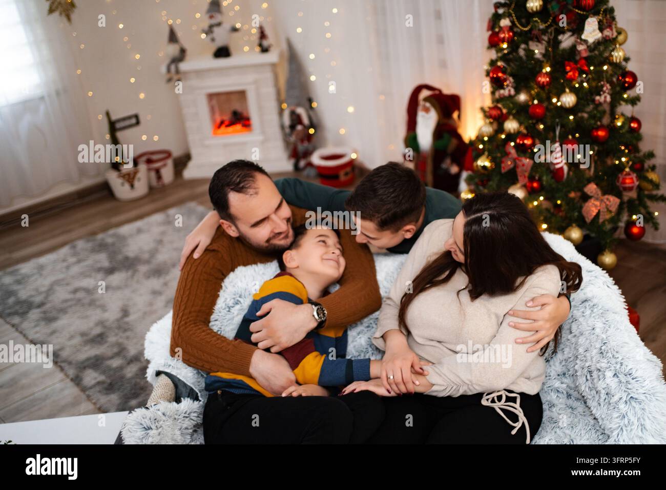 Famiglia che si abbraccia e celebra le festività natalizie a casa Foto Stock