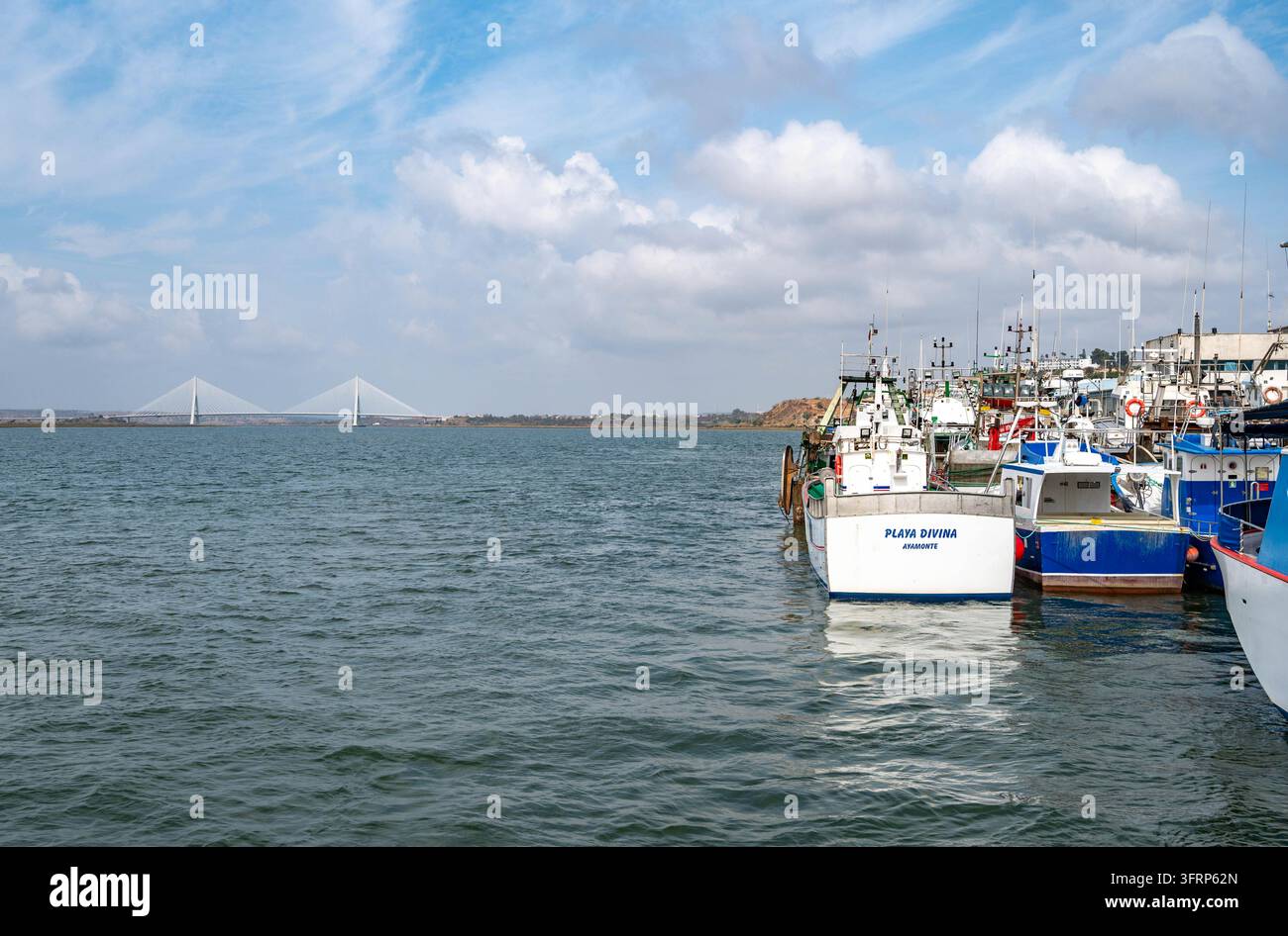 Ayamonte, Spagna, 10-03-2026: Ponte Guadiana sullo sfondo con barche sul fiume tra Portogallo e Spagna, cielo drammatico, spazio di copia per sfondo di viaggio Foto Stock