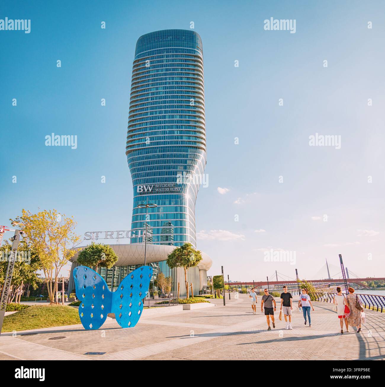 28 luglio 2026, Belgrado, Serbia: Persone che passeggiano lungo la passeggiata godendosi l'architettura moderna di Kula e una scultura di farfalla blu Foto Stock