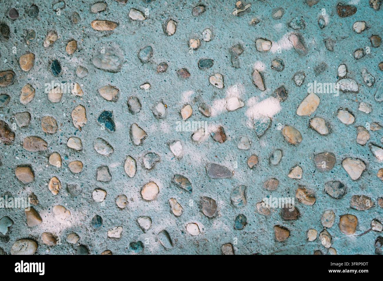 Superficie in cemento aggregato con ciottoli mescolati incastonati in cemento blu-verde – sfondo texture. Foto Stock