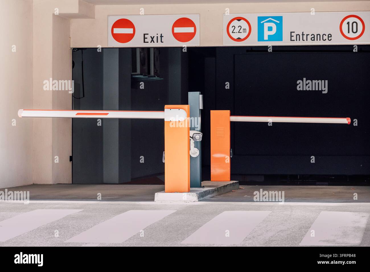 Ingresso moderno per parcheggio con barriera automatica, telecamera di sicurezza e segnali chiari per il controllo dell'accesso di uscita e ingresso Foto Stock