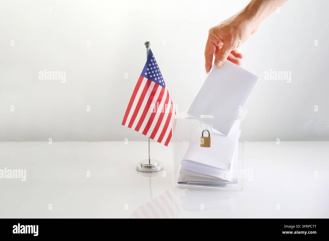 Mano che inserisce una scheda di voto in una scatola trasparente, mostrando l'elezione americana e il processo democratico Foto Stock