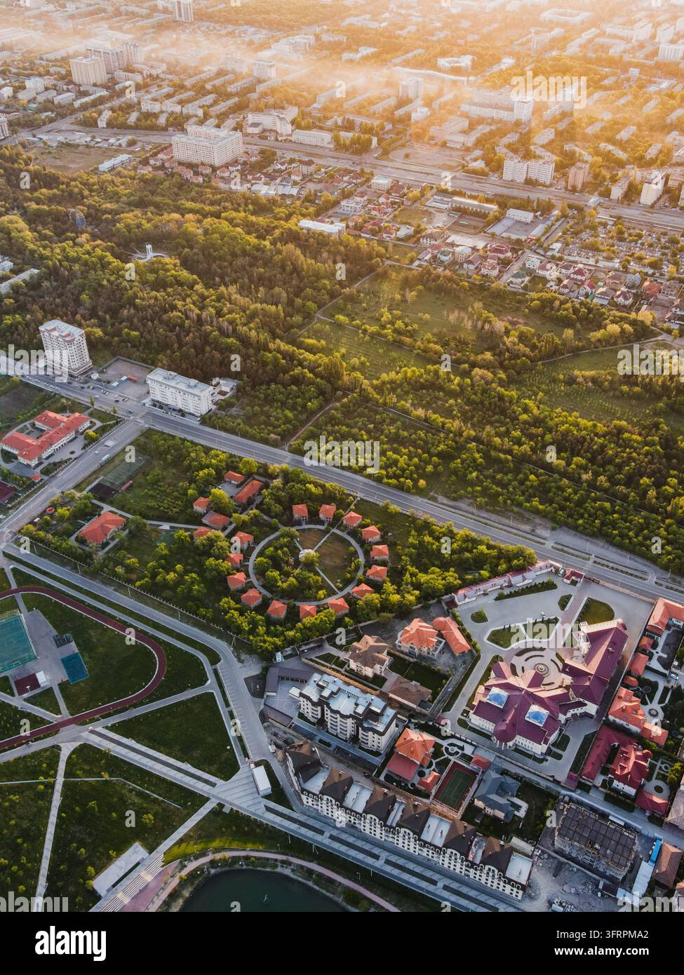 Vista ad angolo alto di un parco paesaggistico con percorsi circolari e giardini circondati da edifici urbani a Bishkek Foto Stock