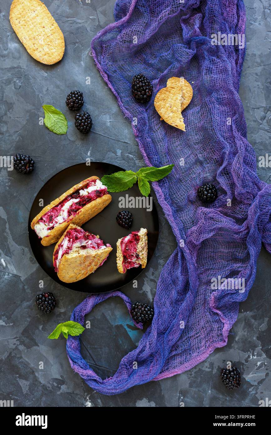 Sandwich di biscotti al gelato fatti in casa e more su uno sfondo di pietra, messa a fuoco selettiva Foto Stock