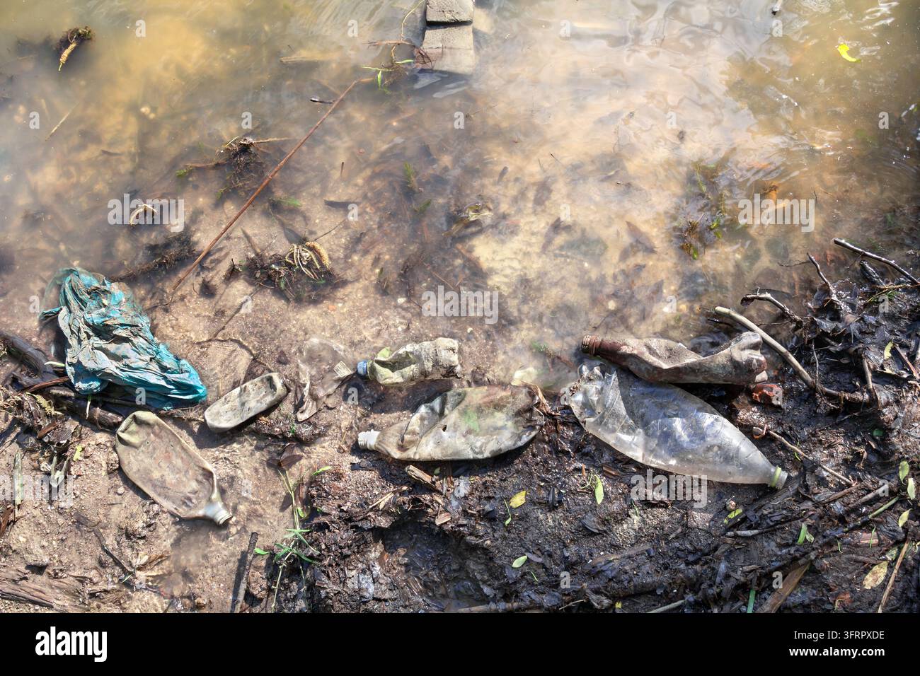 Rifiuti di plastica, bottiglie e sacchetti abbandonati sulla riva e galleggianti nell'acqua. Concetto di inquinamento ambientale, catastrofe ecologica e Foto Stock