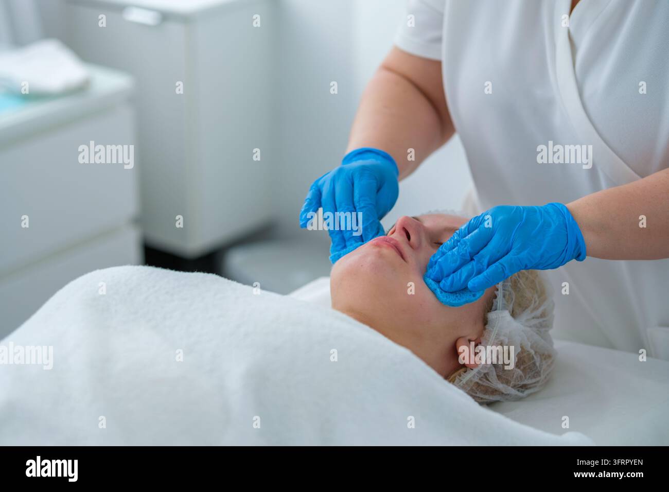 Una sessione di cura professionale in un salone di bellezza presenta una donna, un massaggio facciale, un'estetista, una spugna per il viso, un massaggio del viso e una cosmetologa durante Foto Stock