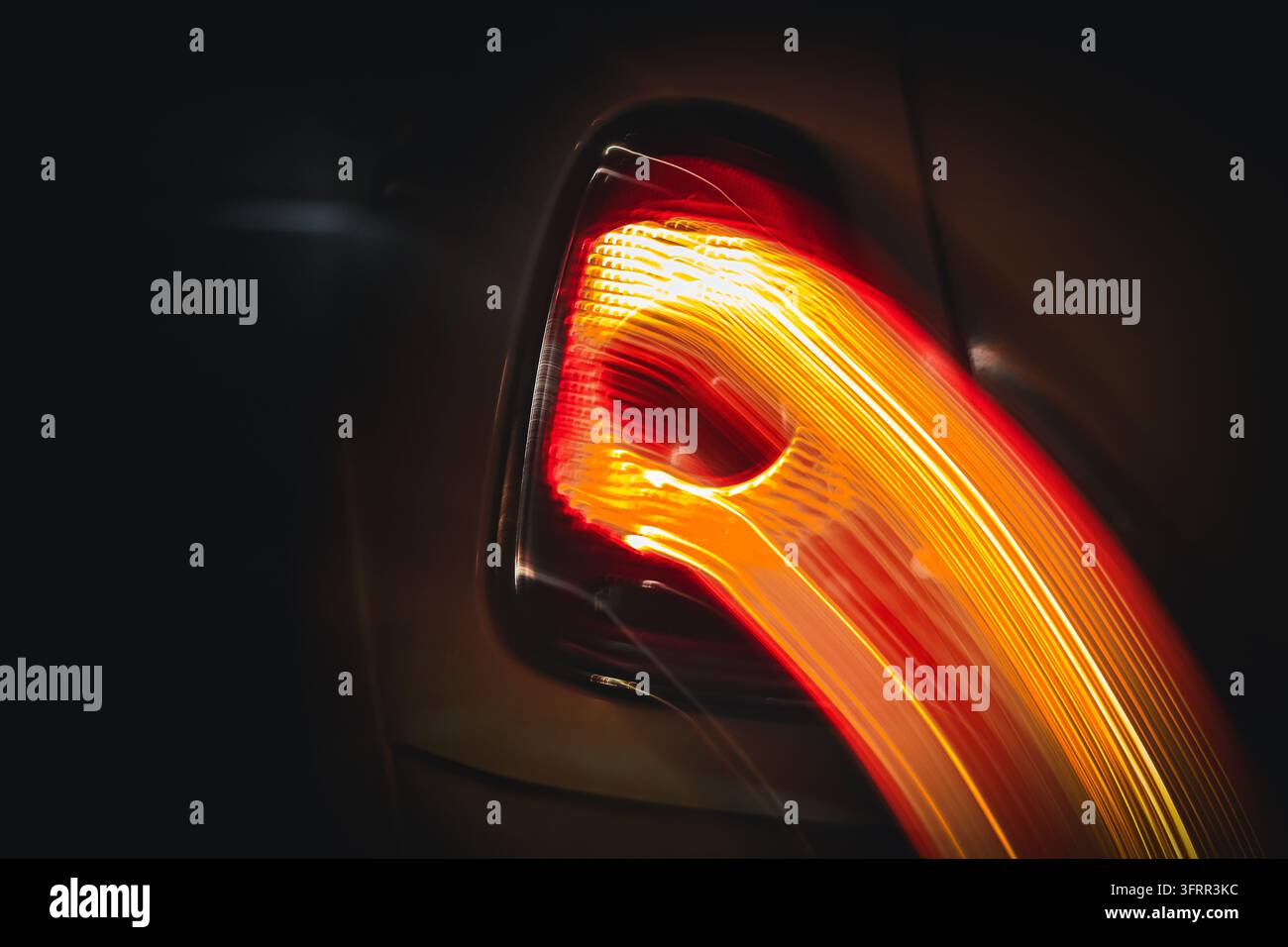 Tracciamenti di luce curvi astratti da una luce posteriore luminosa di un'auto di notte, movimento intenzionale della fotocamera Foto Stock