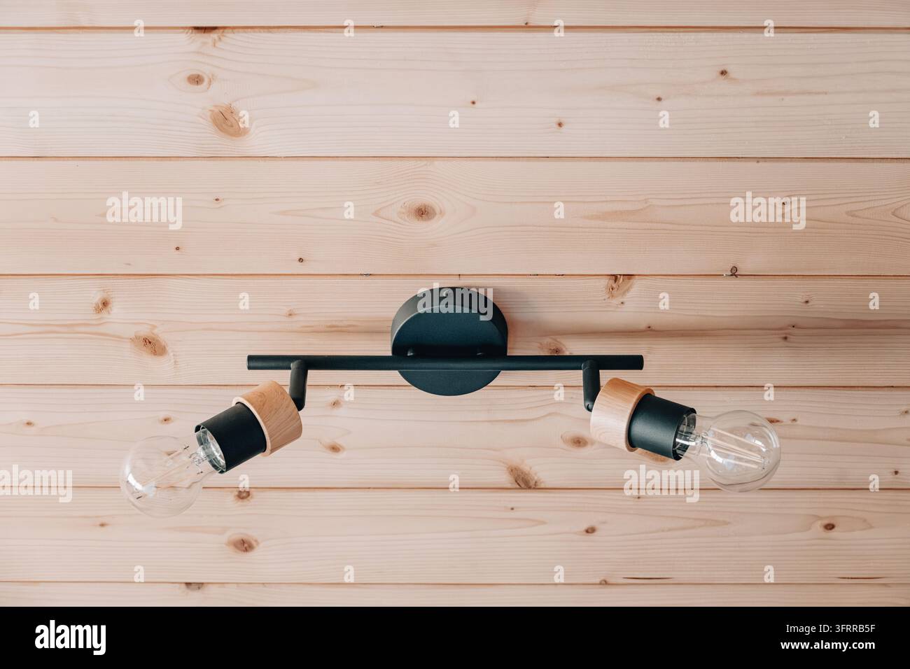 Plato luminoso minimalista con binario a soffitto con dettagli in metallo nero e legno, che illumina uno sfondo di pannello di legno Foto Stock