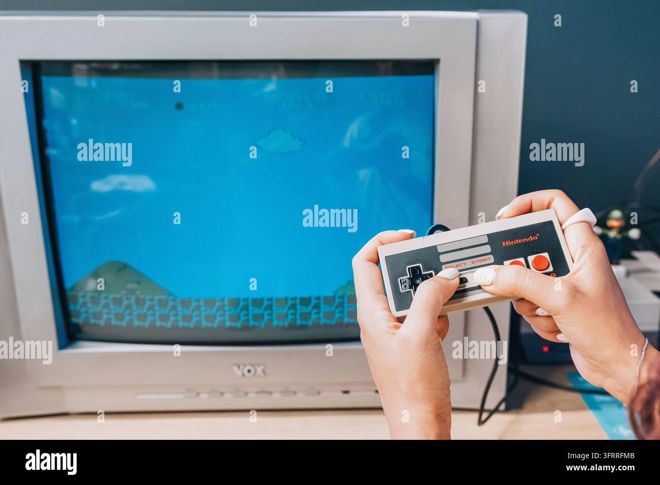 2 agosto 2026, museo Yandex, Belgrado, Serbia: mani di una donna che tengono un controller Nintendo mentre giocano a Super Mario Bros su un televisore CRT retrò. Foto Stock