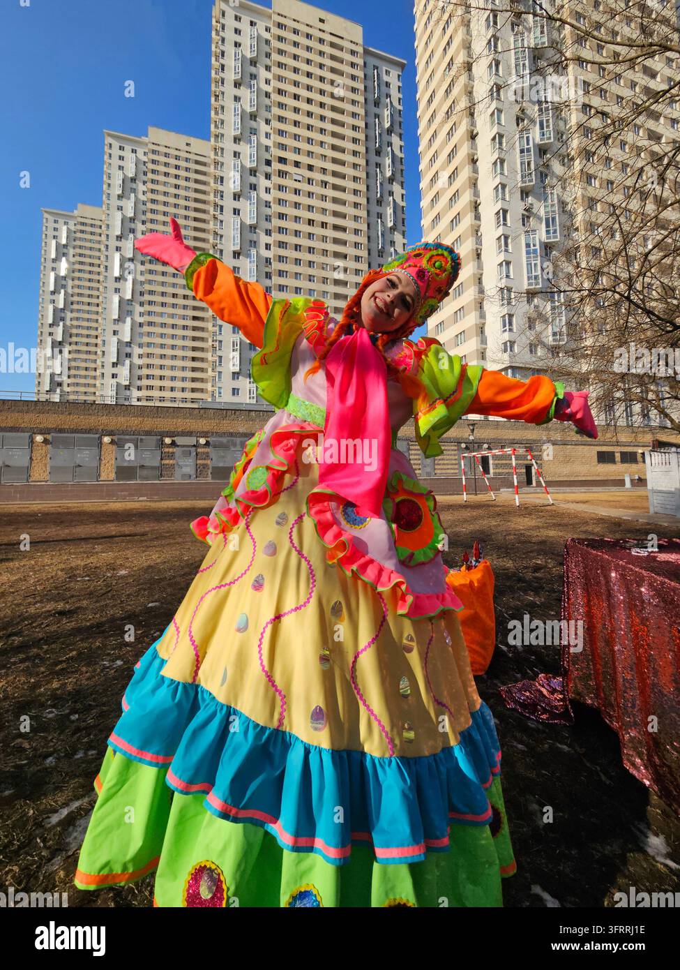 MOSCA - 28 FEB 2025: Una donna in un costume colorato Maslenitsa è in piedi davanti a un edificio. Sta sorridendo ed è felice Foto Stock