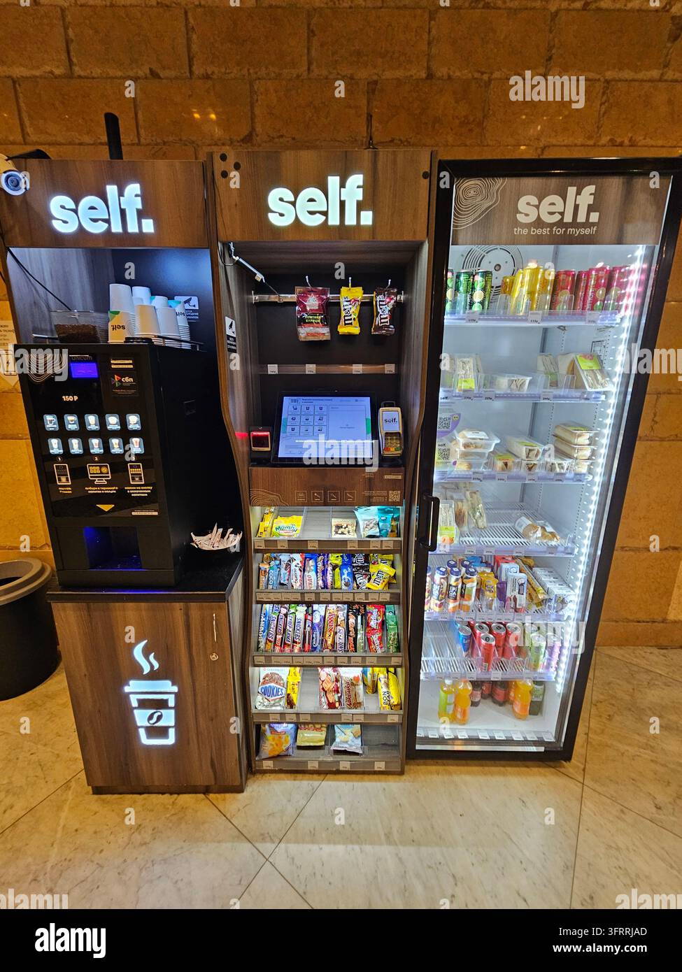 Mosca - 8 marzo 2025: Un distributore automatico self-service con una macchina del caffè e un frigorifero. Il distributore è rifornito di una varietà di snack e bevande Foto Stock