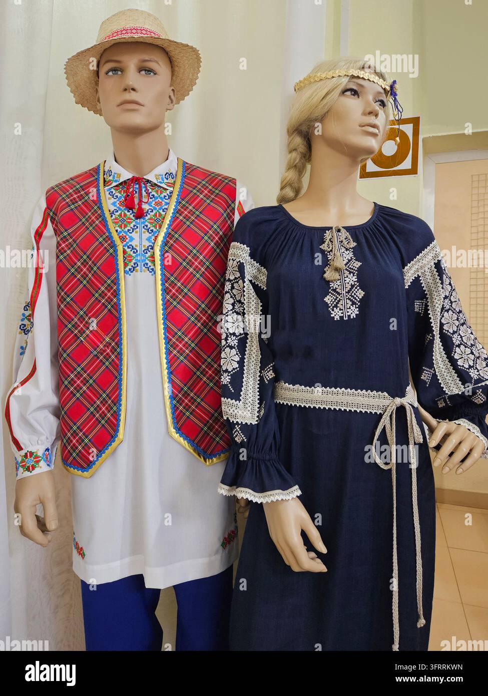MINSK - 25 MARZO 2025: Due manichini vestiti con abiti tradizionali, uno con un gilet rosso e l'altro con un vestito blu Foto Stock
