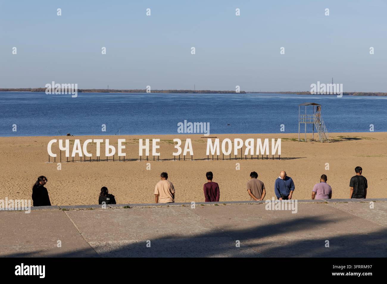 ARCHANGELSK, RUSSA - 25 SETTEMBRE 2026: Studenti indiani che studiano in Russia osservano un oggetto d'arte con testo cirillico che dice "La felicità non è oltre il mare" Foto Stock