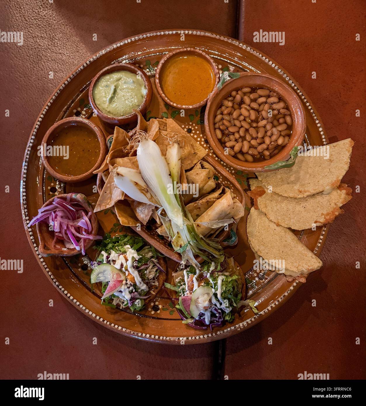 Cena con piccoli bocconi al ristorante Lalaxtli a Chacala, Nayarit, Messico. Tacos fritti, quesadillas, de la olla e tre salse piccanti. - Immagine stock catturata con smartphone