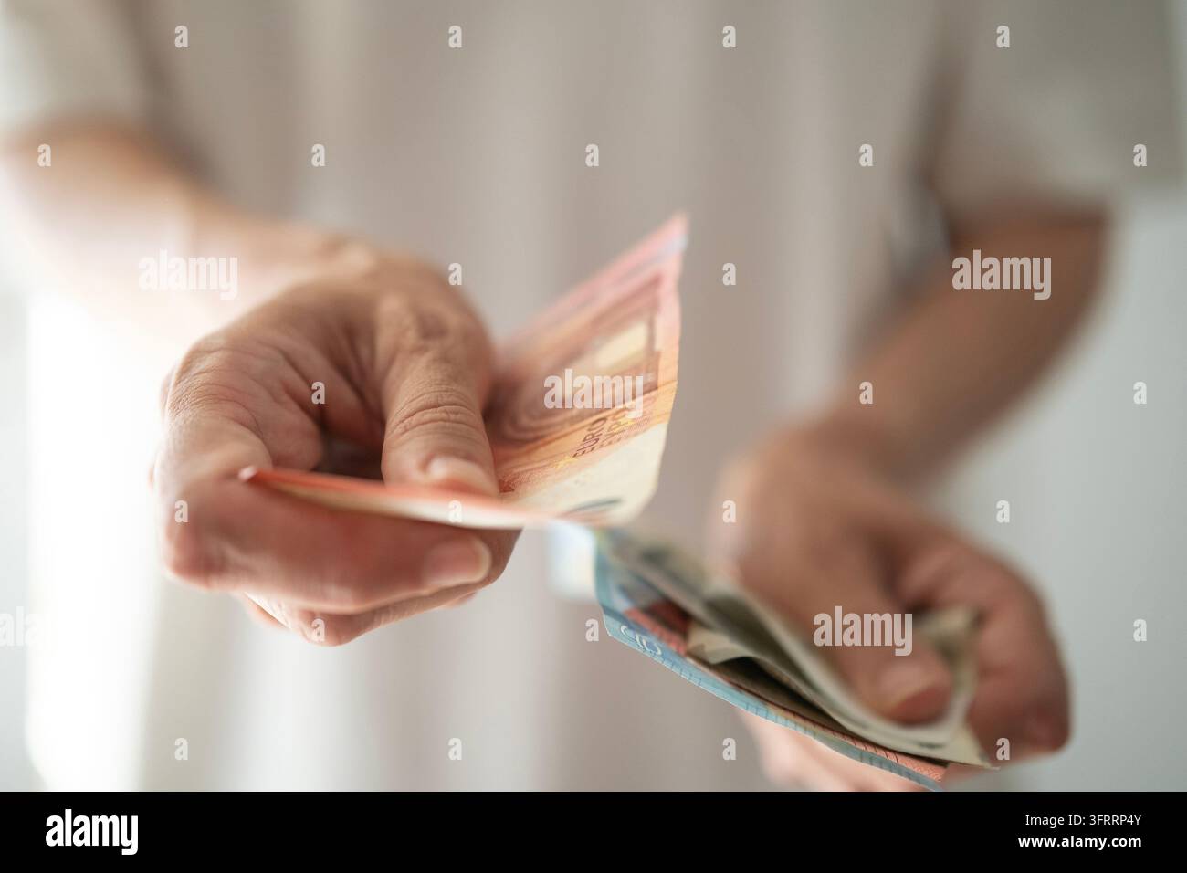 Primo piano delle mani di una donna che paga con banconote in euro, pagamento in contanti e spese quotidiane, concetto di finanza personale e gestione del denaro Foto Stock