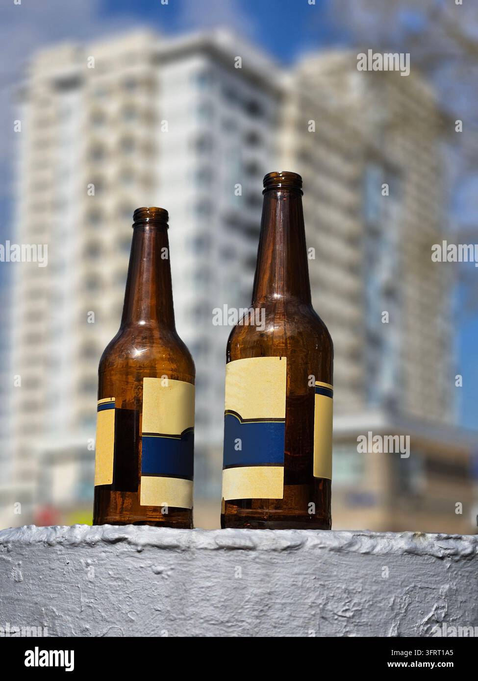 Due bottiglie di birra vuote sono appoggiate su una superficie bianca. Le bottiglie sono marroni e hanno un'etichetta blu vicino all'ingresso nel cortile della casa nel complesso residenziale Foto Stock
