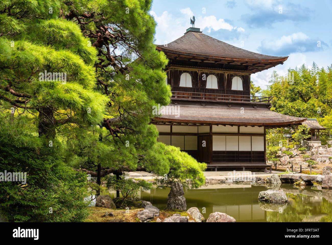 Tranquillo tempio buddista Ginkaku-ji a Kyoto, Giappone: paviglione in legno a due piani vicino a uno stagno da giardino con rocce e verde estivo. Wabi-sabi e calma Zen Foto Stock