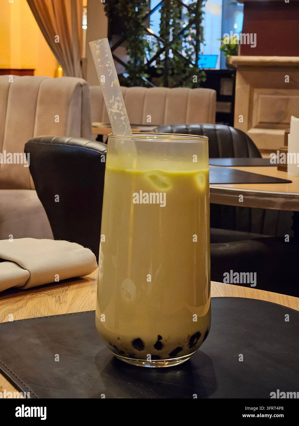 Bicchiere di bubble tea verde con una cannuccia. Il bicchiere è su un tavolo Foto Stock
