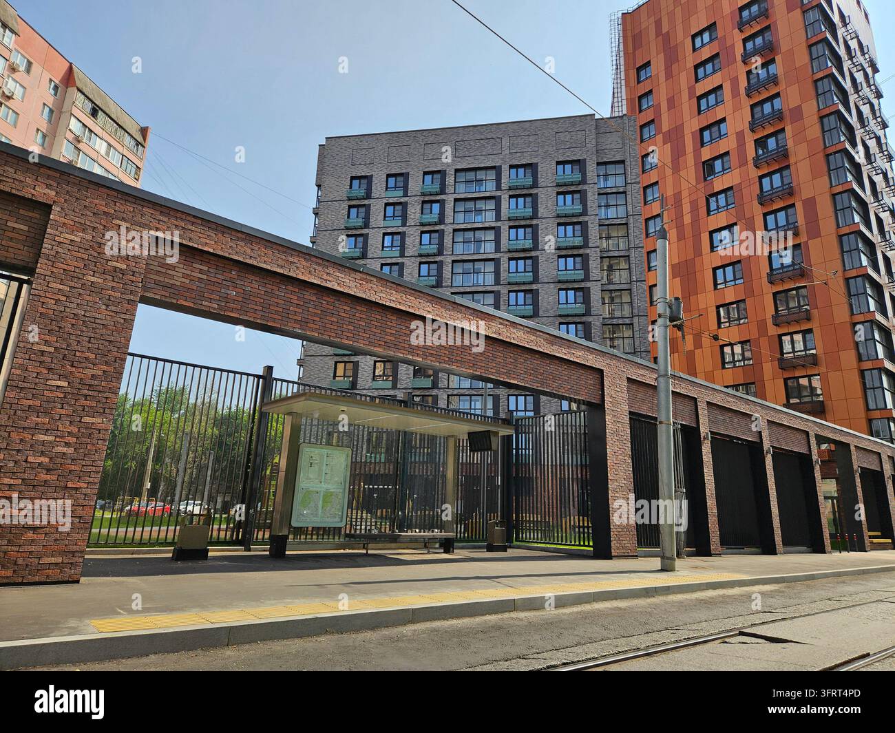 Edificio in mattoni con una recinzione sulla parte anteriore. Davanti alla ristrutturazione dell'edificio c'è una fermata dell'autobus-tram Foto Stock