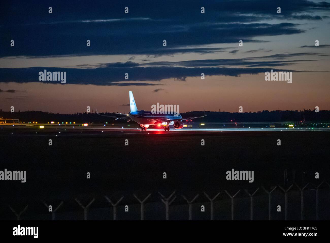 Aereo passeggeri della KLM Royal Dutch Airlines che accelera lungo la pista illuminata per il decollo contro un cielo crepuscolare colorato. Praga, Repubblica ceca Foto Stock