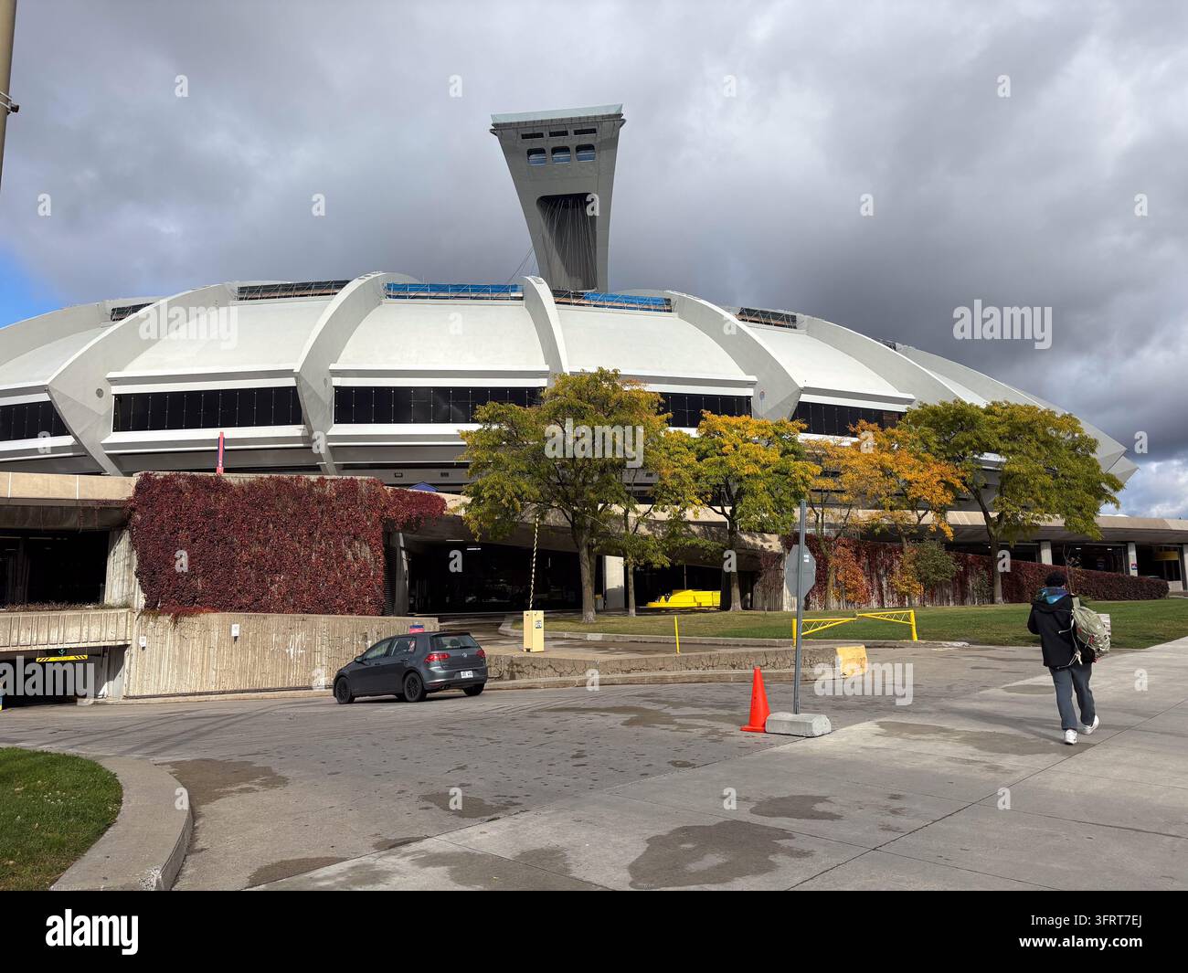 Vista esterna dell'iconico stadio olimpico di Montreal che mostra la sua torre inclinata e l'architettura distintiva circondata da fogliame autunnale sotto un Foto Stock