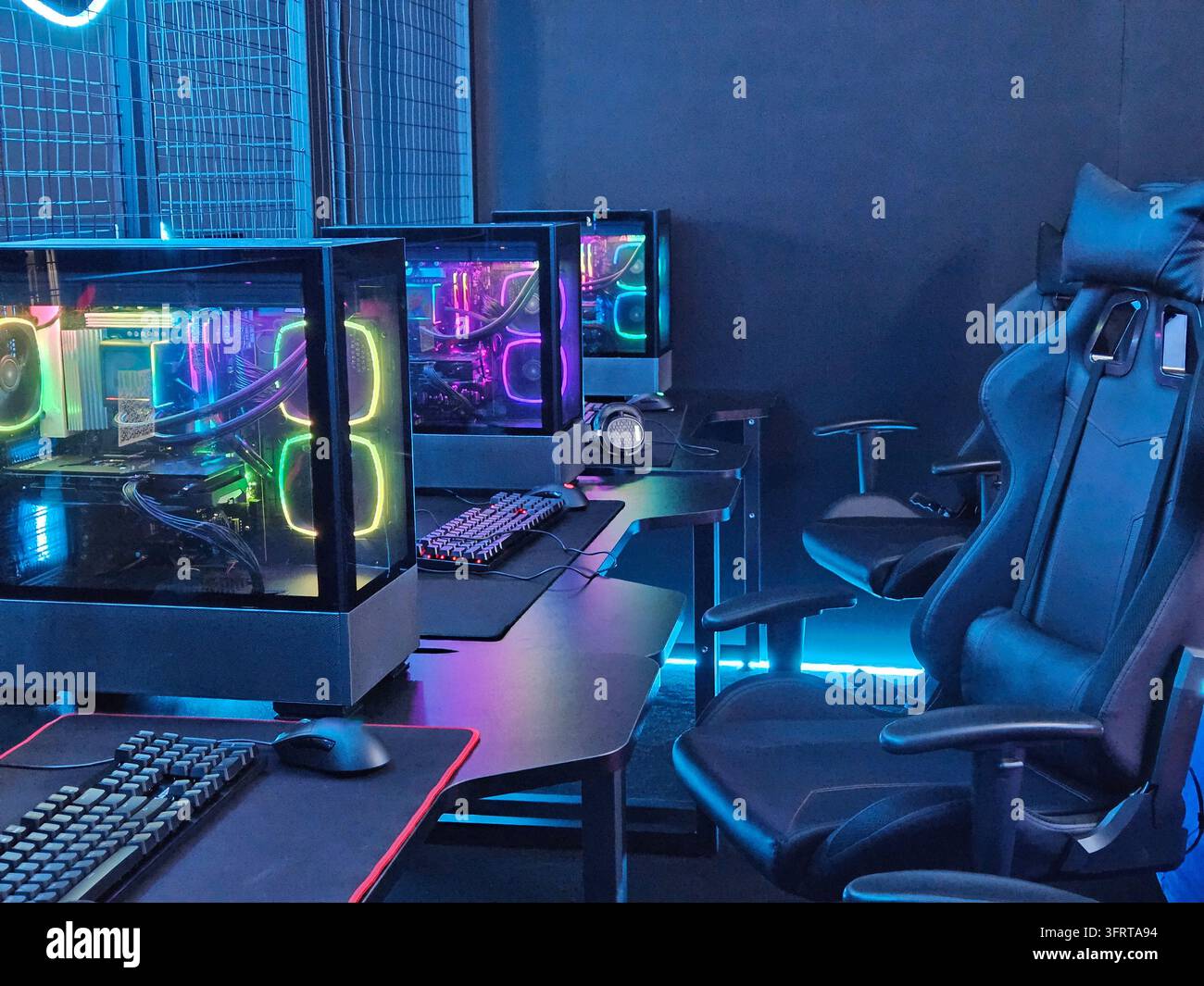 Aula informatica con luci al neon e una sedia. La stanza è piena di computer e sedie. Le luci al neon conferiscono alla stanza un'atmosfera futuristica ed energica Foto Stock