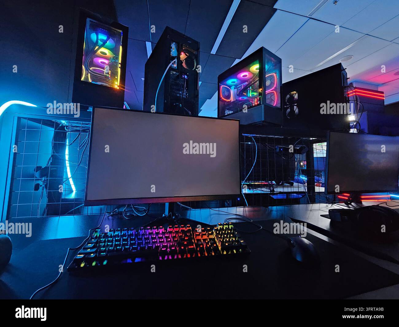 Configurazione del computer con una tastiera nera e un monitor nero. La tastiera ha un arcobaleno di colori Foto Stock