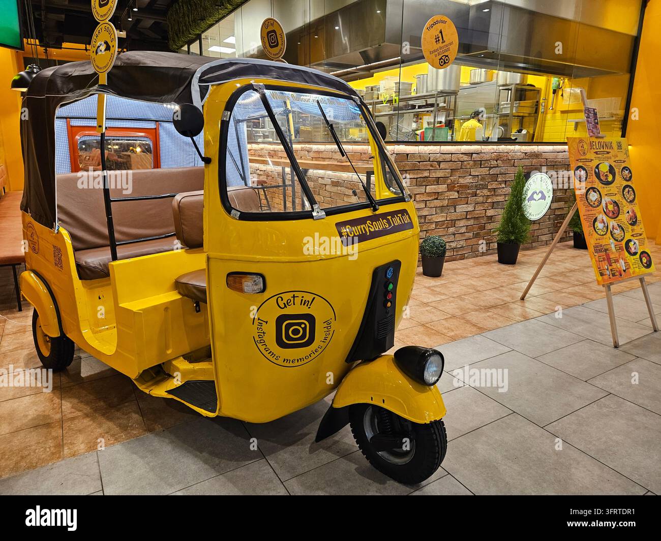 BELGRADO - 23 SET 2025: Veicolo giallo a tre ruote con una telecamera sulla parte anteriore. Il veicolo è parcheggiato davanti a un ristorante Foto Stock