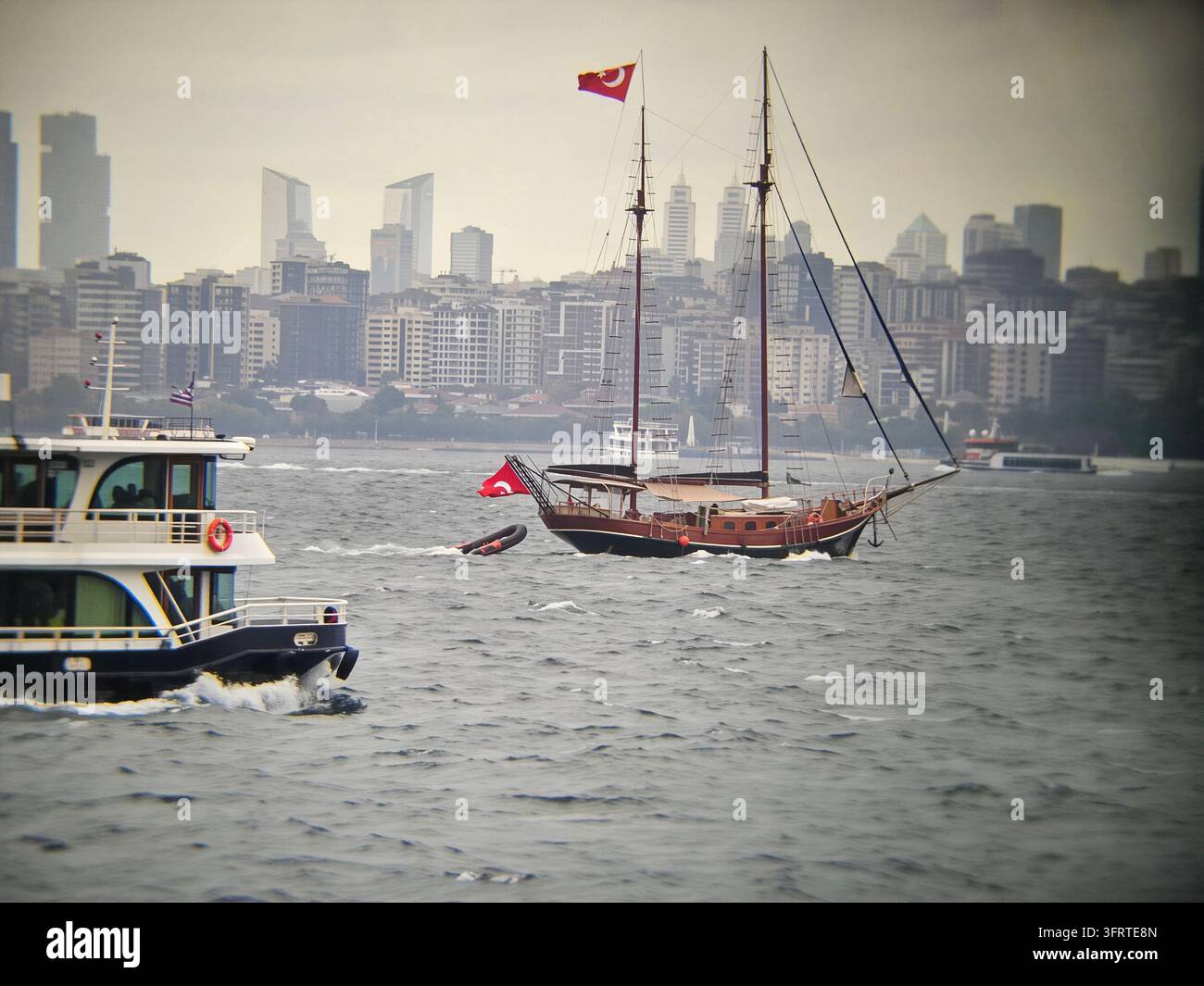 Grande nave naviga nell'oceano con una bandiera sull'albero. Lo skyline della città è visibile sullo sfondo a Istanbul Foto Stock