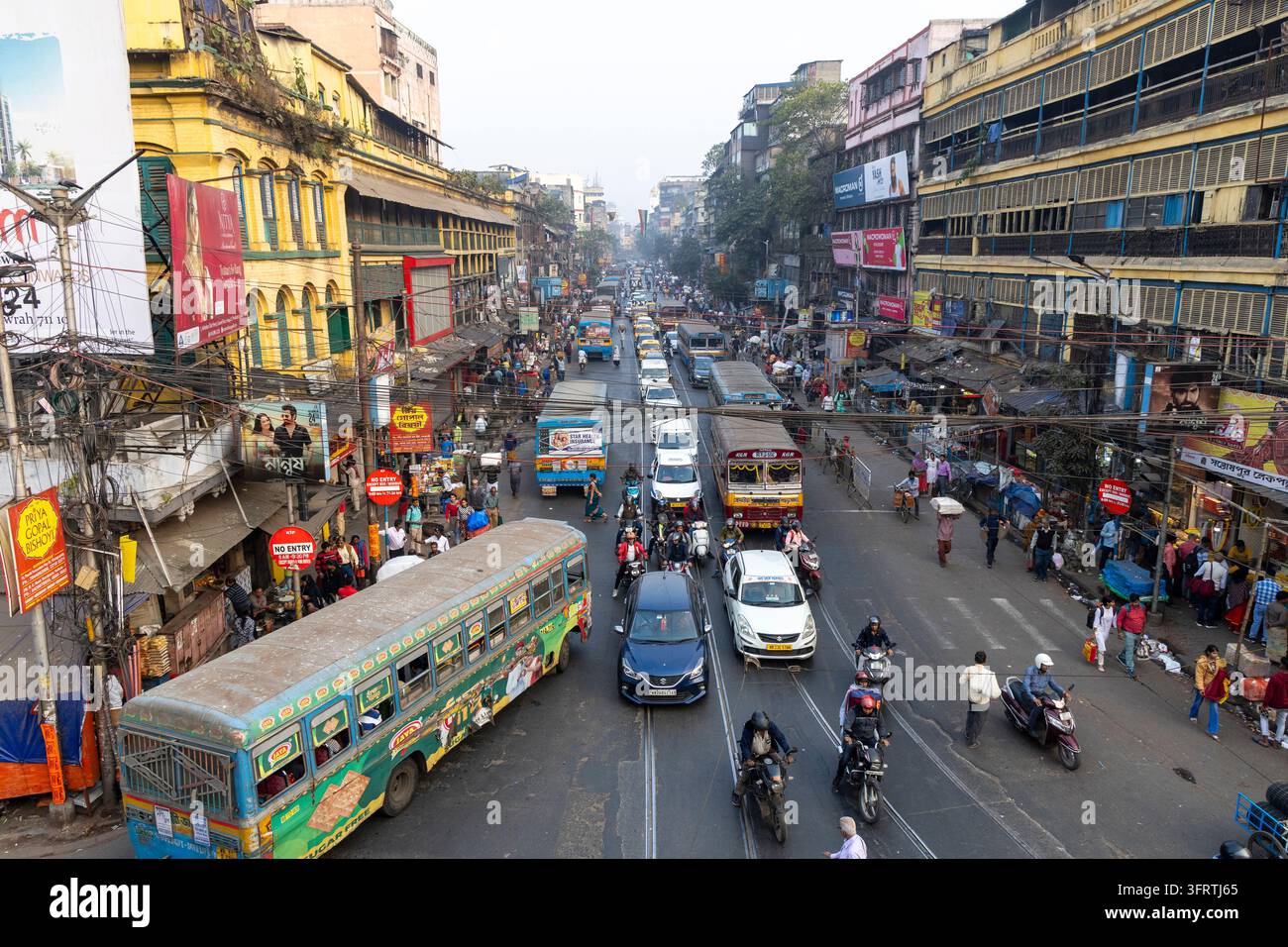 Vista ad angolo alto del traffico intenso su un ampio viale con autobus dipinti, taxi e scooter accanto a vecchi edifici coloniali e cavi aerei ingarbugliati, Ovest Foto Stock