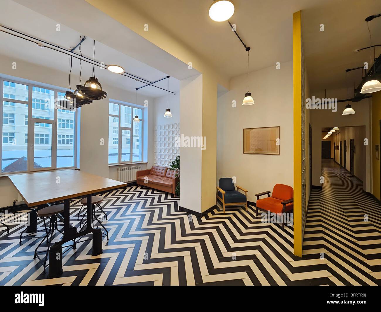 SAMARA - 14 GEN 2026: Interno in stile loft moderno con audace motivo a zigzag bianco e nero sul pavimento. Travi a vista con lampade a sospensione industriali e lampadari pendenti Foto Stock