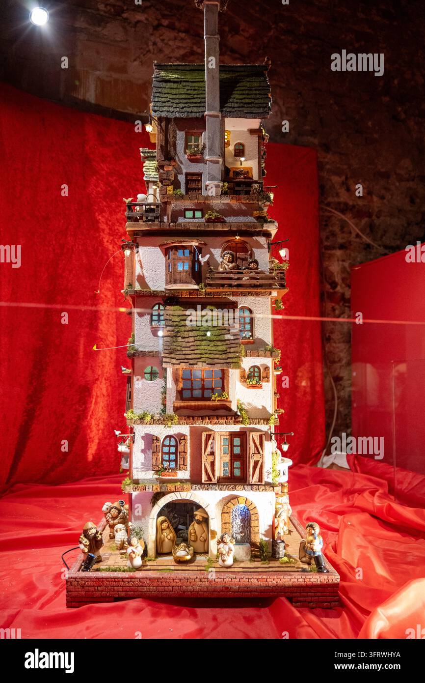 Verona, Italia - 1 gen 26: Casa in miniatura verticale con molte finestre, balconi, figure e una scena della Natività alla base, esposta a Verona, Italia Foto Stock