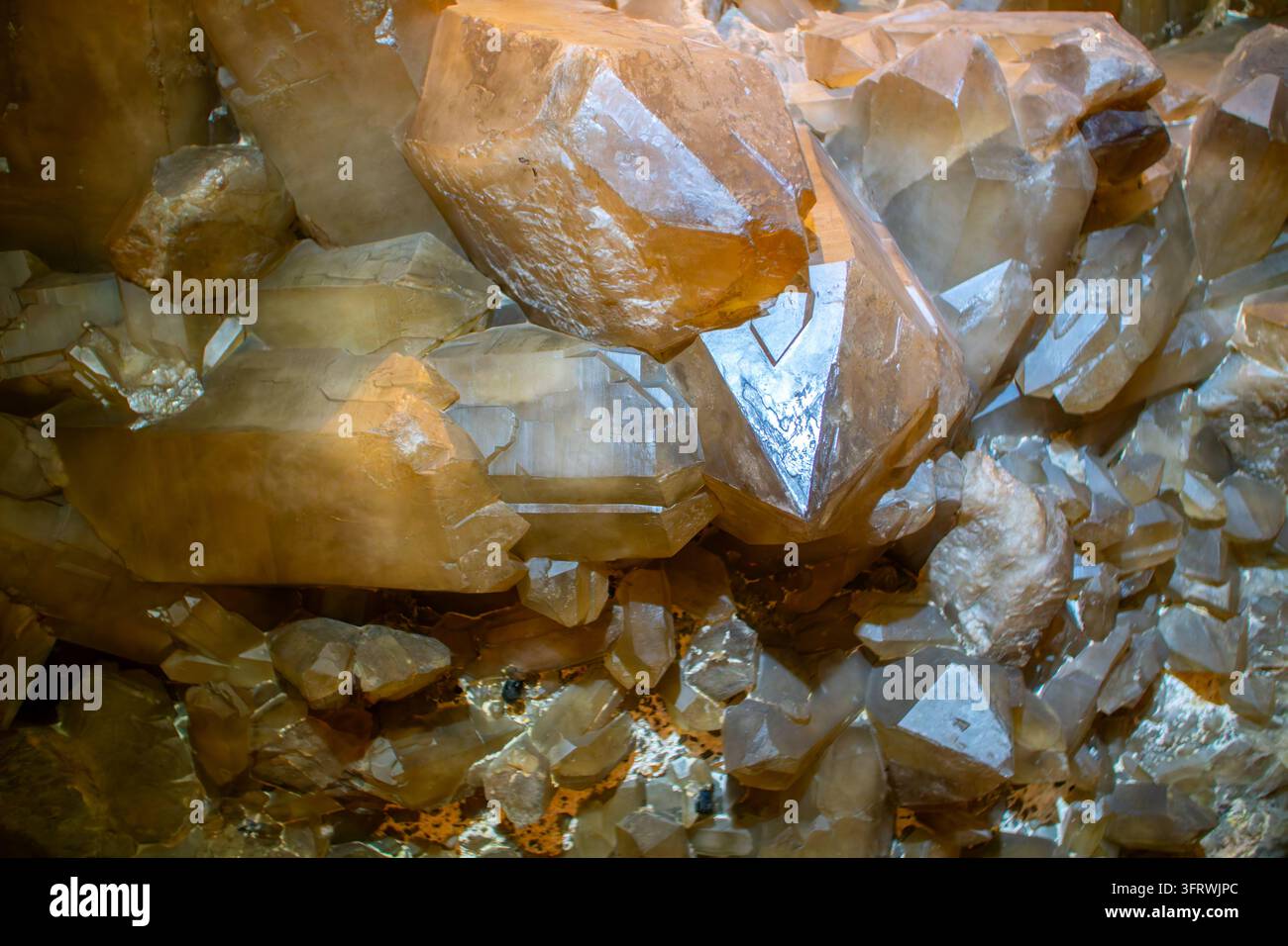 Primo piano di cristalli di calcite dorati traslucidi in un ammasso minerale denso, che mostrano crescita cristallina e superfici di sfaldatura; possibile associazione con il quarzo Foto Stock