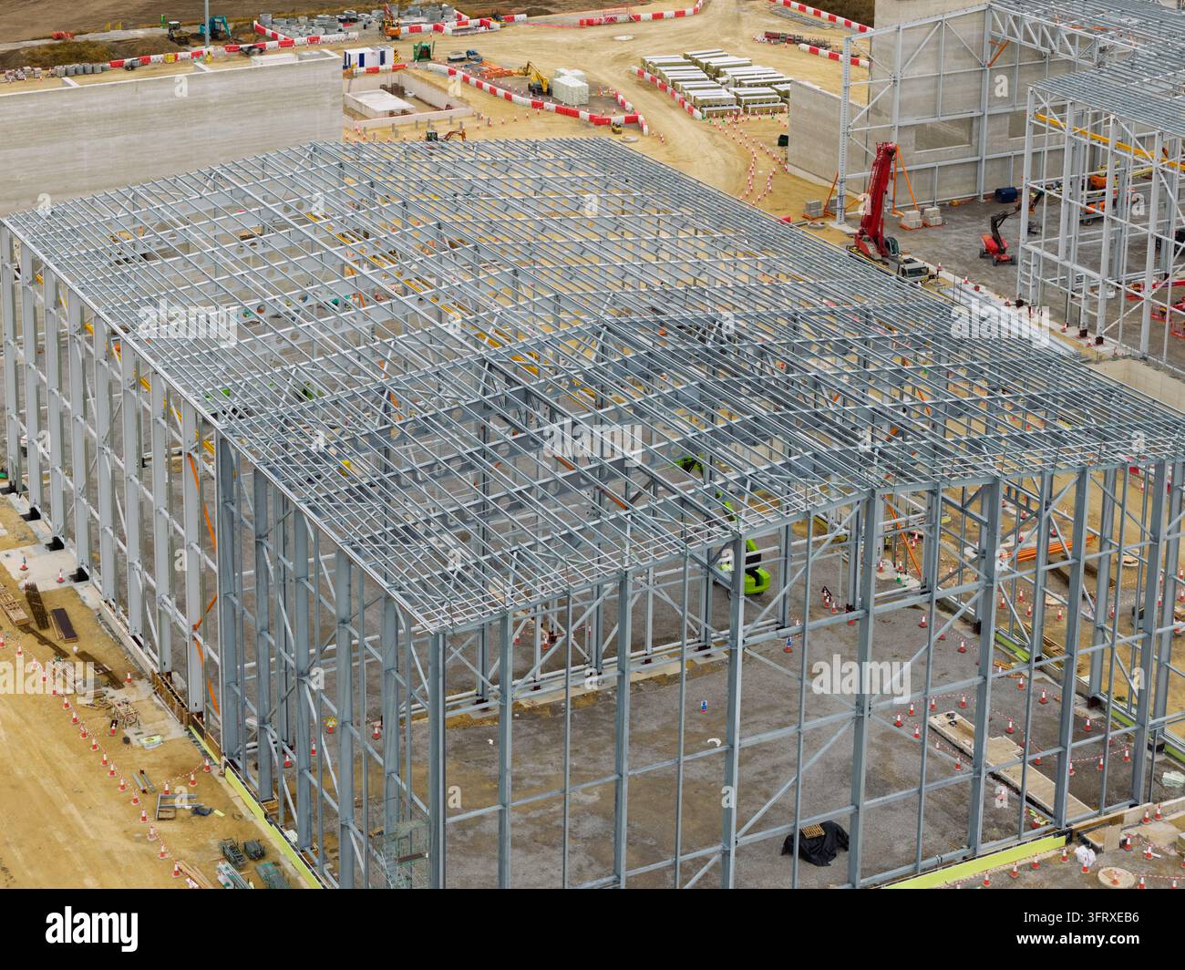 Vista aerea di un enorme cantiere edile che mostra la struttura scheletrica di un edificio e pesanti macchine lavoranti sulle fondamenta durante il giorno. Foto Stock