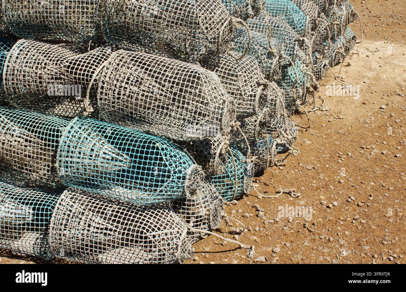 Pila di trappole per pesci tradizionali fatte a mano con filo e maglia sul terreno, che mostrano il patrimonio artigianale della pesca marina a Kerkennah, Tunisia. Foto Stock